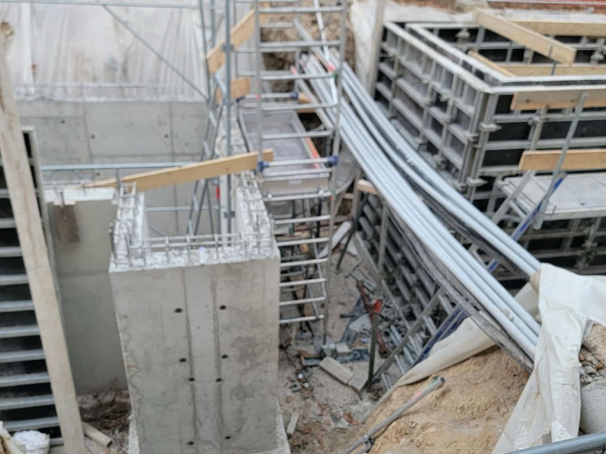 Cofragem metálica e pilar descofrado junto a andaime, numa obra em meio urbano